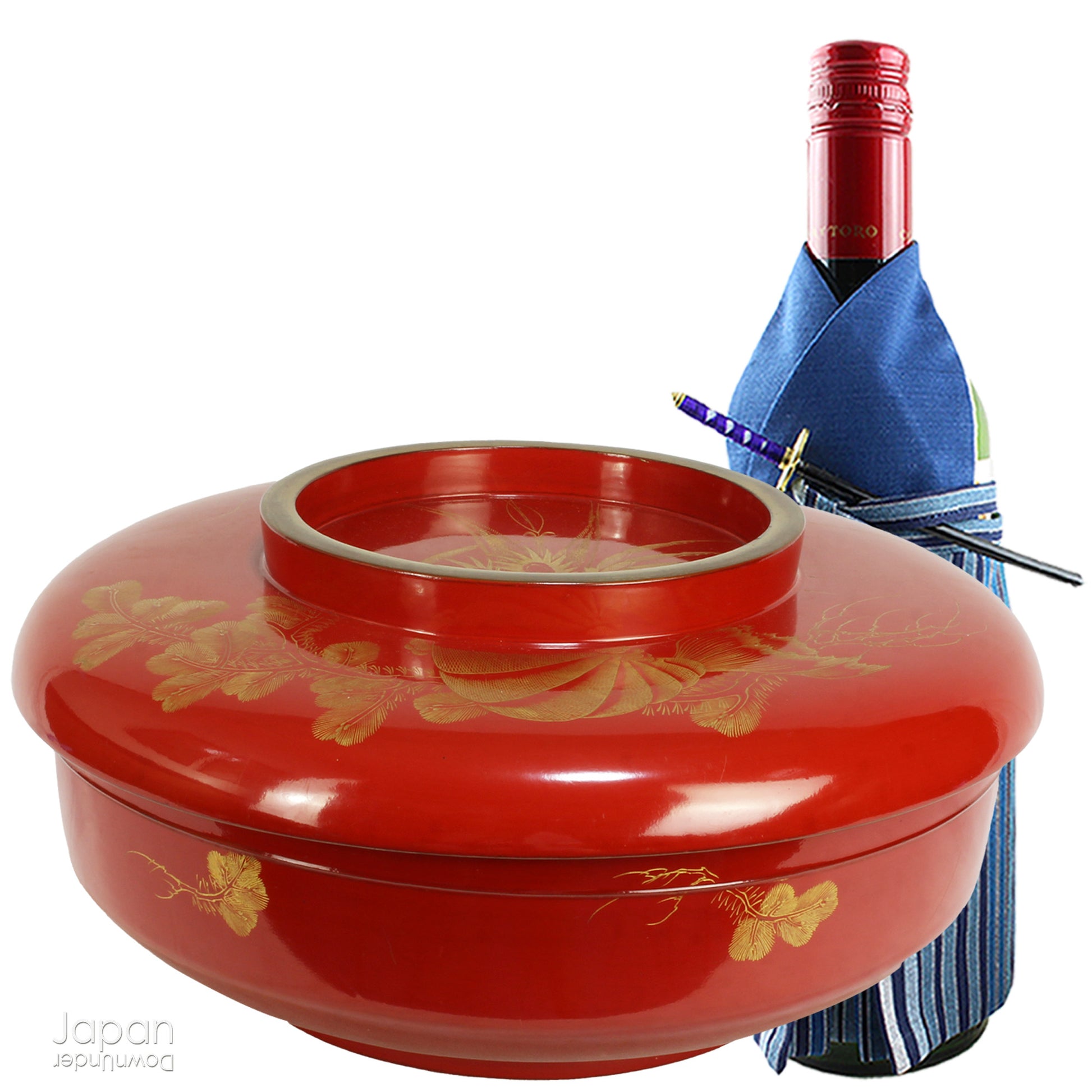 Red lacquerware container with gold floral patterns next to a bottle of wine in a blue garment.  The bottle is 29 cm and is there for size reference.