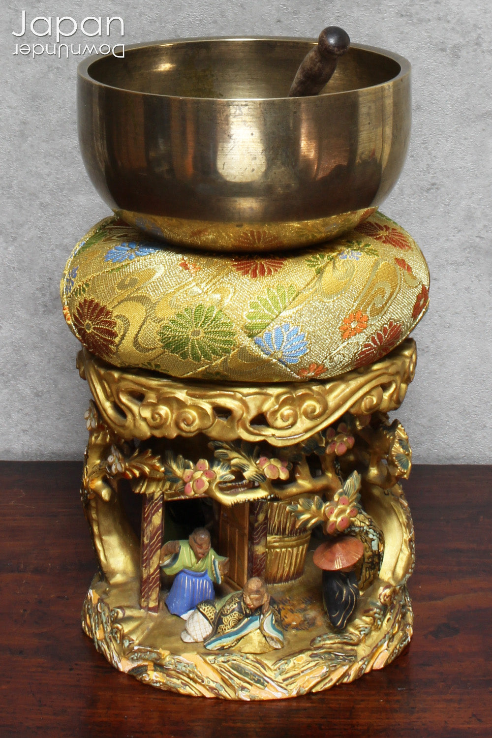 An 1800’s Buddhist altar singing bowl, harmoniously displayed on a traditional intricately carved custom order stand. Complete with a luxurious brocade cushion, this set exudes timeless elegance and spiritual significance.