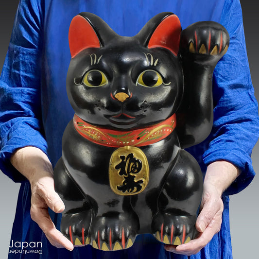 Welcome prosperity and good fortune into your space with this impressive oversized black antique Japanese lucky cat. Its charm is undeniable, from the adorable face to the beckoning paw, symbolizing wealth and good luck. A unique addition to your decor,  the maneki neko cat will certainly bring a smile to your face. Perfect for cat lovers and anyone seeking a touch of luck in their lives.