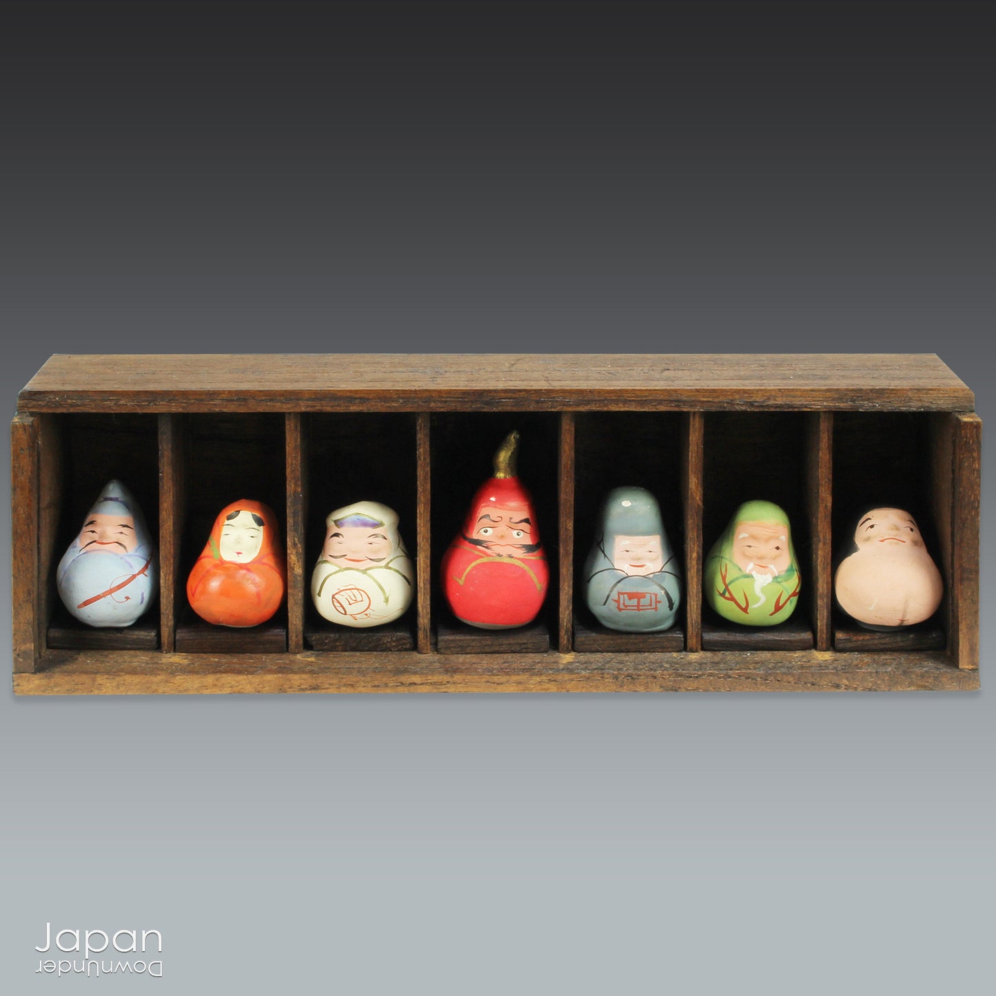Invite good fortune and timeless tradition into your home with this quaint set of miniature antique Daruma charms. Housed in a charming wooden and glass display box, this unique collection adds an elegant and meaningful touch to your decor, perfect for any space seeking a blend of tradition, luck, and positive energy.
Crafted in the 1920s, this set features hand-painted clay Daruma figures representing the Seven Lucky Gods of Japan, each with its own powerful symbolism.