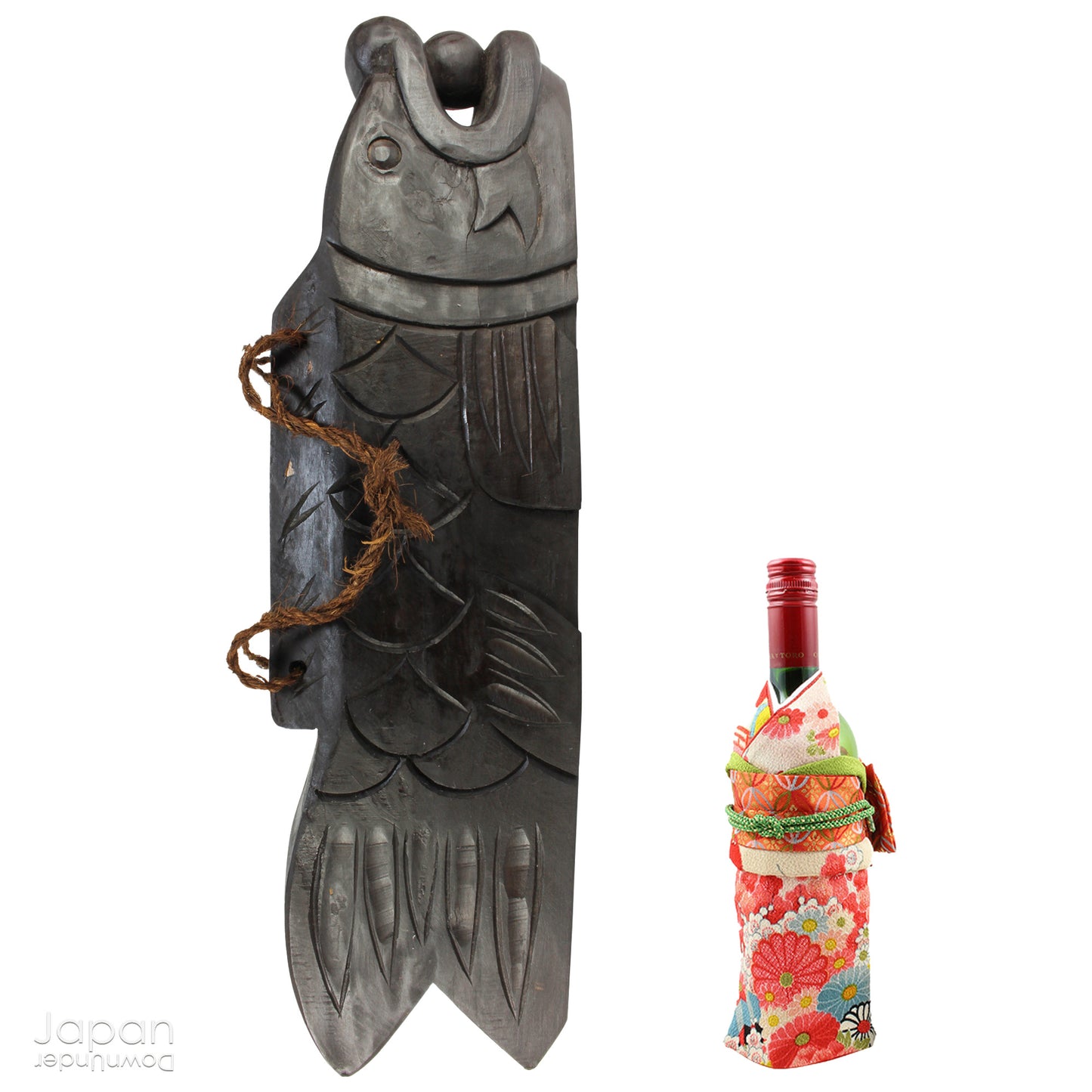 A vintage Buddhist temple gyoban; a  plank of wood shaped like a fish.  It is carved from   wood. The scales, big eye and fin, etched  into the wood,  give the fish form. There is a  round pearl in the fish mouth,  symbolizing unity.