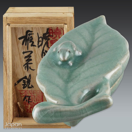 Add a touch of nature and serenity to your space with this exquisite celadon kogo, a beautifully handcrafted incense box designed for the Japanese tea ceremony. Featuring a delicate frog perched on a graceful leaf, this unique piece radiates charm and elegance, making it a perfect addition to any home or tea lover's collection.
In the Japanese tradition, kogo are intricately designed lidded boxes used to hold incense during tea ceremonies, reflecting the beauty of nature and the changing seasons. This par