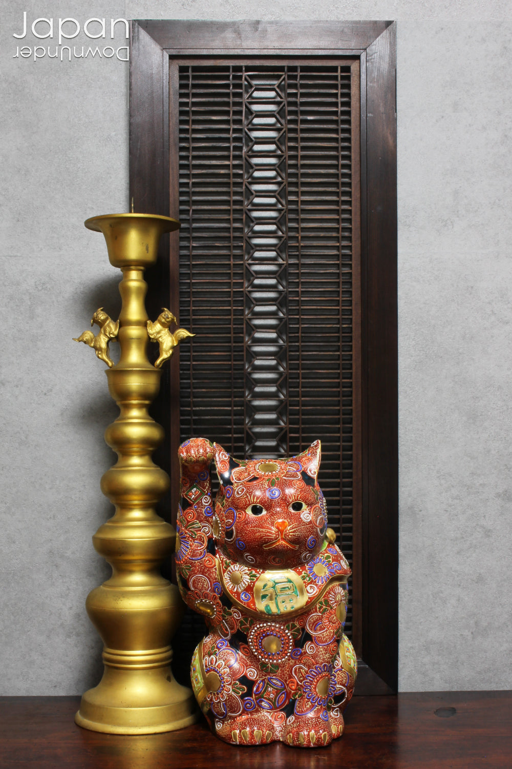 An antique Buddhist temple candle holder.    The gilded brass candle holder is a cylindrical shape, formed of spheres,  gradually decreasing in size as they move upwards. Just below the candle cup hang a pair of Japanese komainu, or lion dogs.