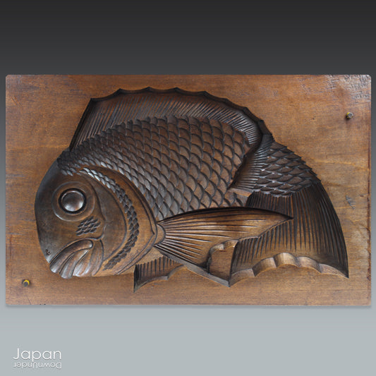 Add a touch of Japanese charm to your rustic decor with this antique sweet mold featuring a lucky fish carving. Perfect for adding a unique and cultural element to your space.