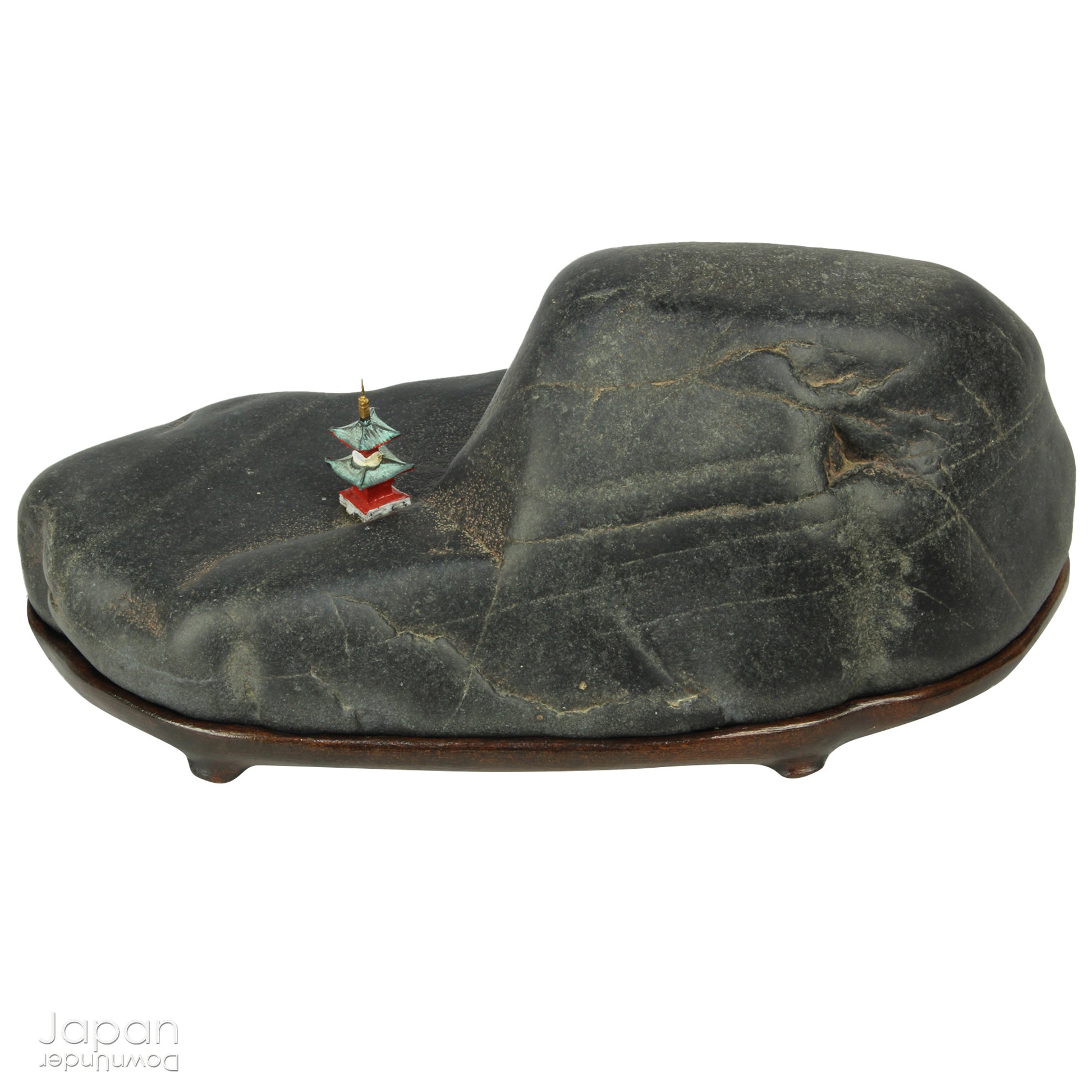 Introduce a quiet elegance and poetic depth to your space with this vintage Japanese suiseki - a contemplative stone shaped by nature and imbued with a serene, spiritual aura. Resting on a finely hand-carved daiza (wooden base) and accompanied by a small metal pagoda, this piece emanates stillness, balance, and an understated visual allure.