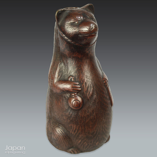 Infuse your space with the timeless elegance of Japanese craftsmanship and folklore through this antique Bizen raccoon dog tokkuri. Not only does it serve its traditional function as a sake pourer, but it also doubles as a captivating piece of art or a charming bud vase, making it a truly versatile addition to your collection.