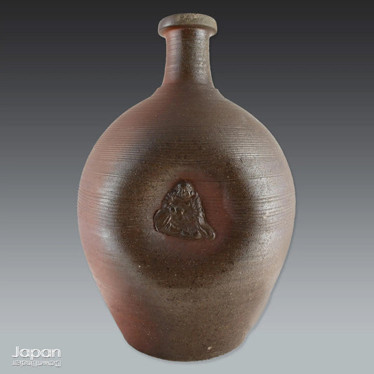 Add depth and story to your interior with this striking Taisho-era Bizen ware sake tokkuri, adorned with Hotei - the cheerful god of happiness, children, and good fortune, and one of Japan’s beloved Seven Lucky Gods. More than just a vessel, this antique bottle is a captivating example of Japanese folk craftsmanship, equally compelling as a sculptural display piece or a uniquely soulful vase.