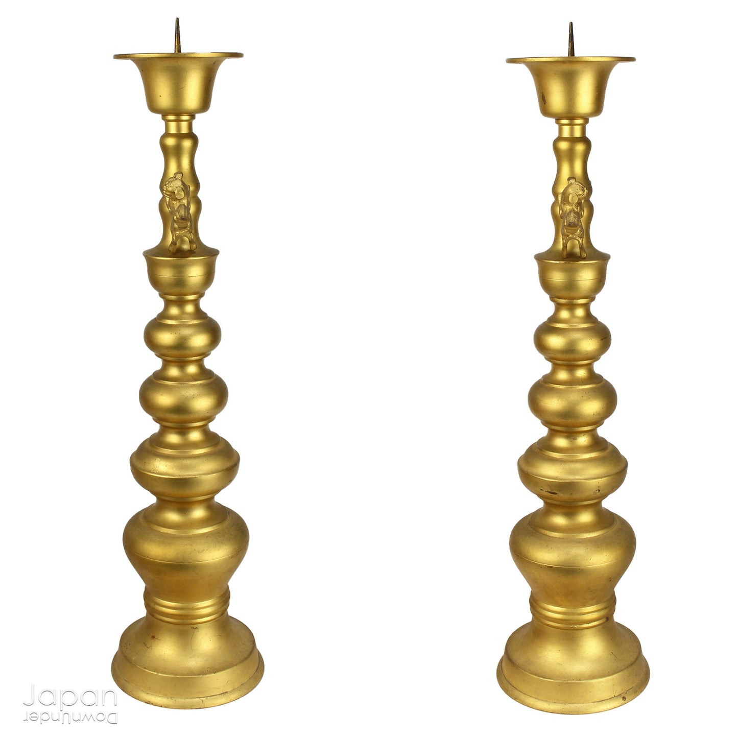 An antique Buddhist temple candle holder.    The gilded brass candle holder is a cylindrical shape, formed of spheres,  gradually decreasing in size as they move upwards. Just below the candle cup hang a pair of Japanese komainu, or lion dogs.