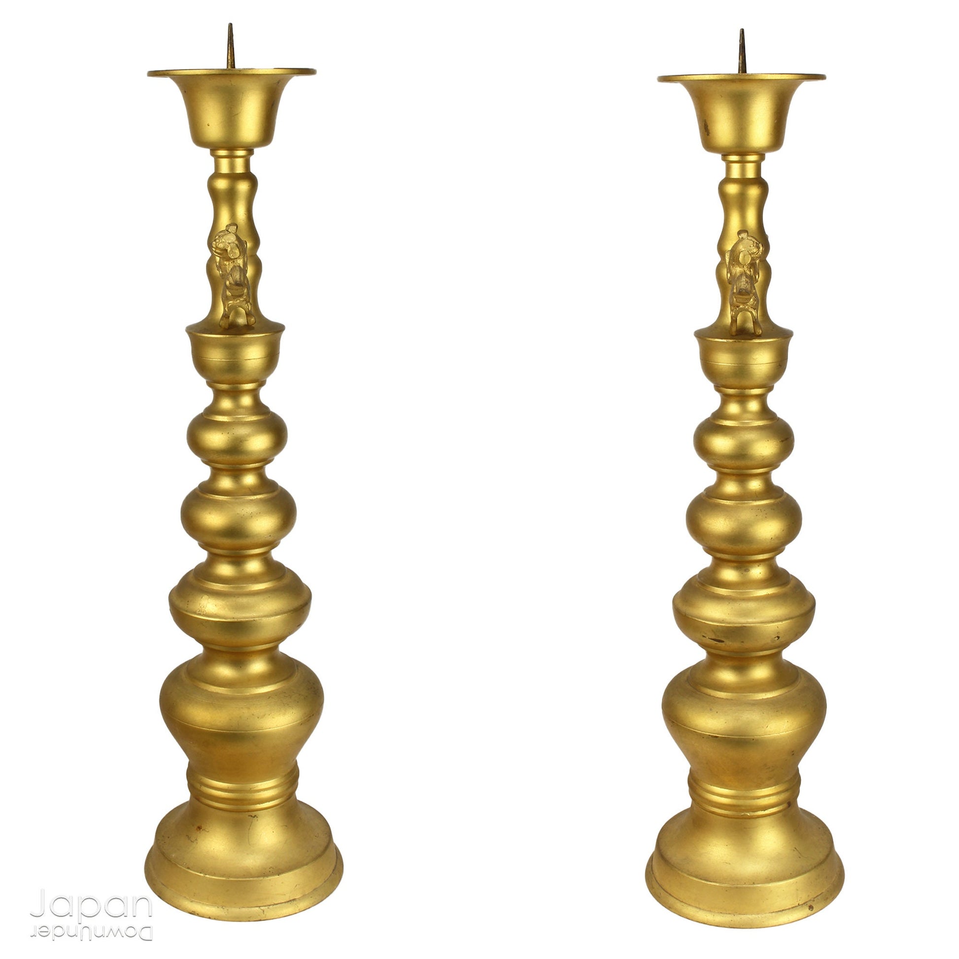 An antique Buddhist temple candle holder.    The gilded brass candle holder is a cylindrical shape, formed of spheres,  gradually decreasing in size as they move upwards. Just below the candle cup hang a pair of Japanese komainu, or lion dogs.