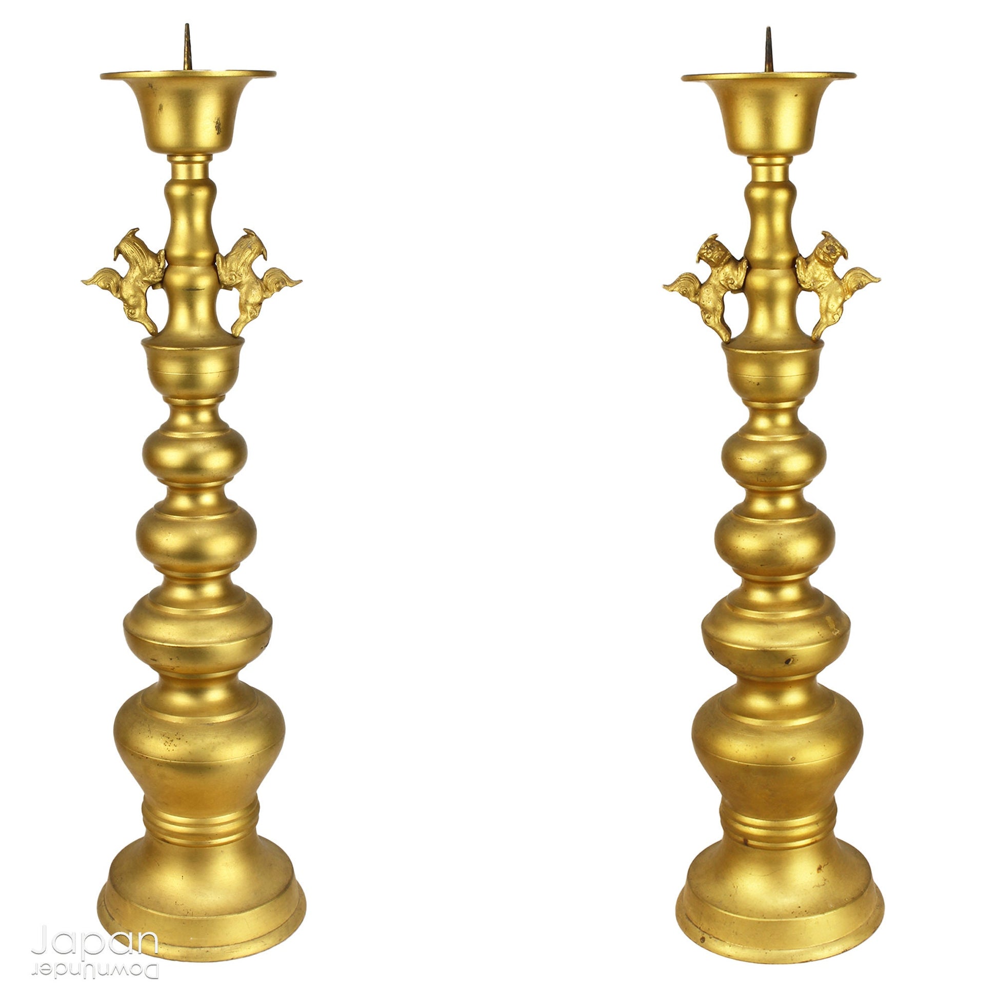 An antique Buddhist temple candle holder.    The gilded brass candle holder is a cylindrical shape, formed of spheres,  gradually decreasing in size as they move upwards. Just below the candle cup hang a pair of Japanese komainu, or lion dogs.