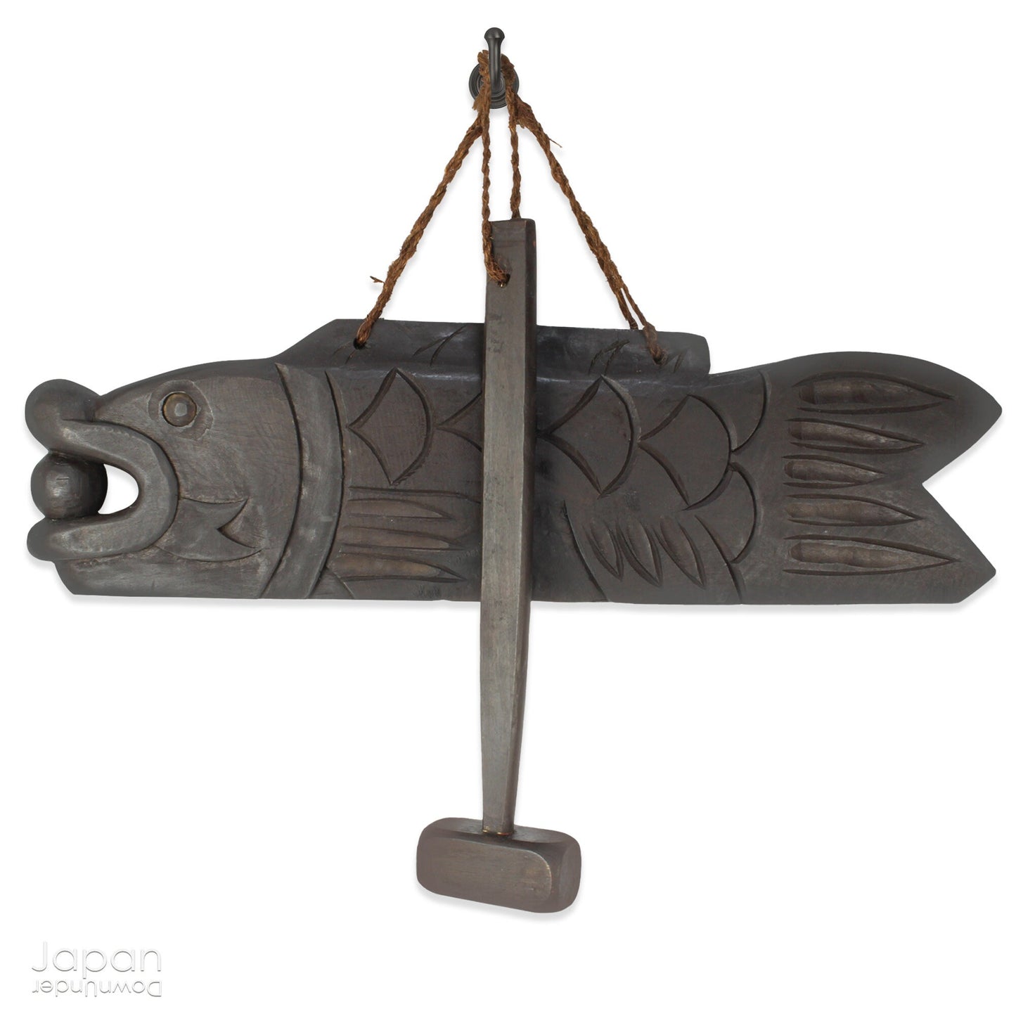 A vintage Buddhist temple gyoban; a  plank of wood shaped like a fish.  It is carved from   wood. The scales, big eye and fin, etched  into the wood,  give the fish form. There is a  round pearl in the fish mouth,  symbolizing unity.