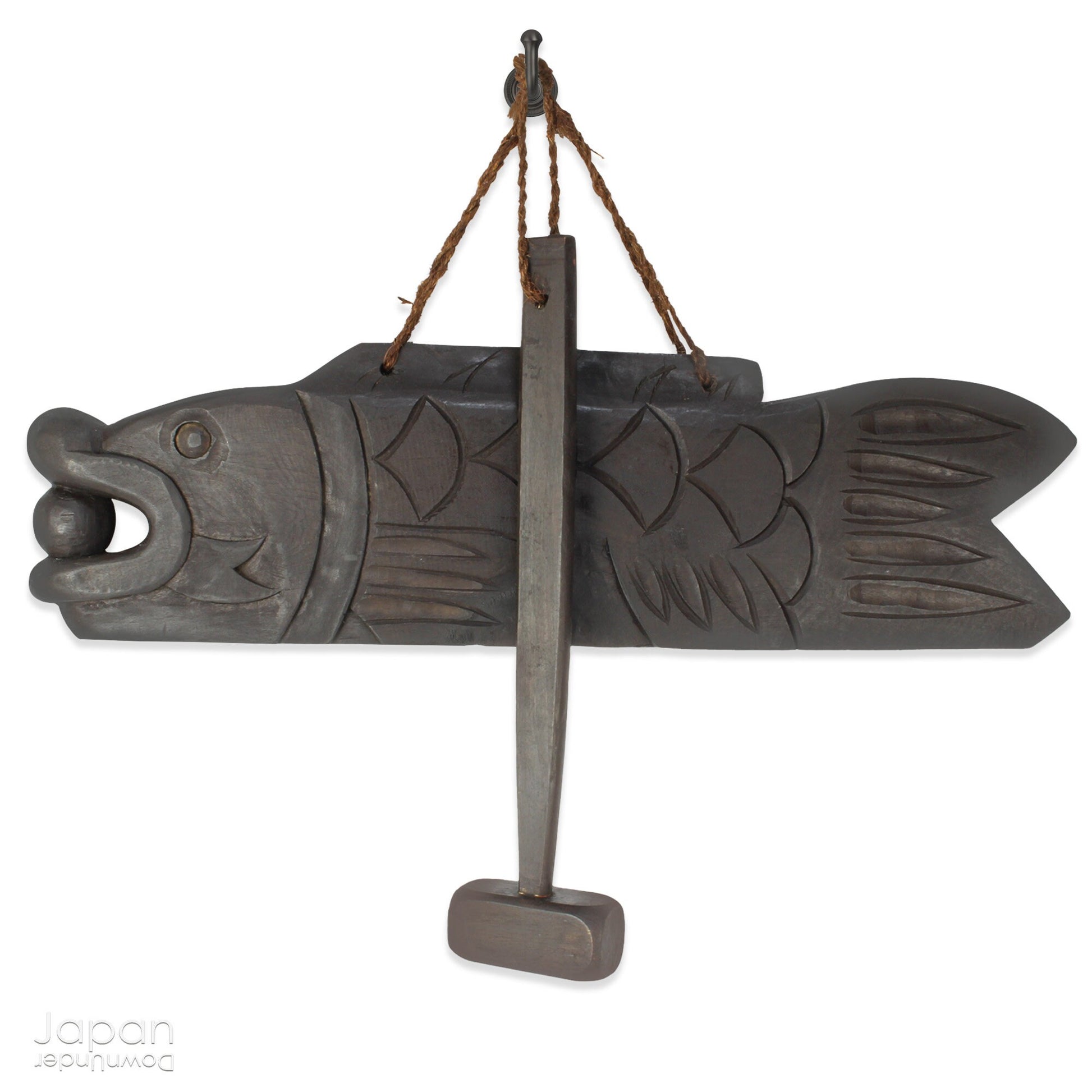 A vintage Buddhist temple gyoban; a  plank of wood shaped like a fish.  It is carved from   wood. The scales, big eye and fin, etched  into the wood,  give the fish form. There is a  round pearl in the fish mouth,  symbolizing unity.