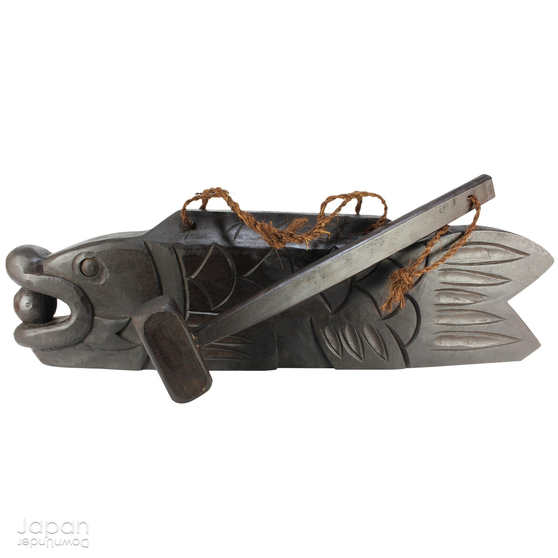 A vintage Buddhist temple gyoban; a  plank of wood shaped like a fish.  It is carved from   wood. The scales, big eye and fin, etched  into the wood,  give the fish form. There is a  round pearl in the fish mouth,  symbolizing unity.