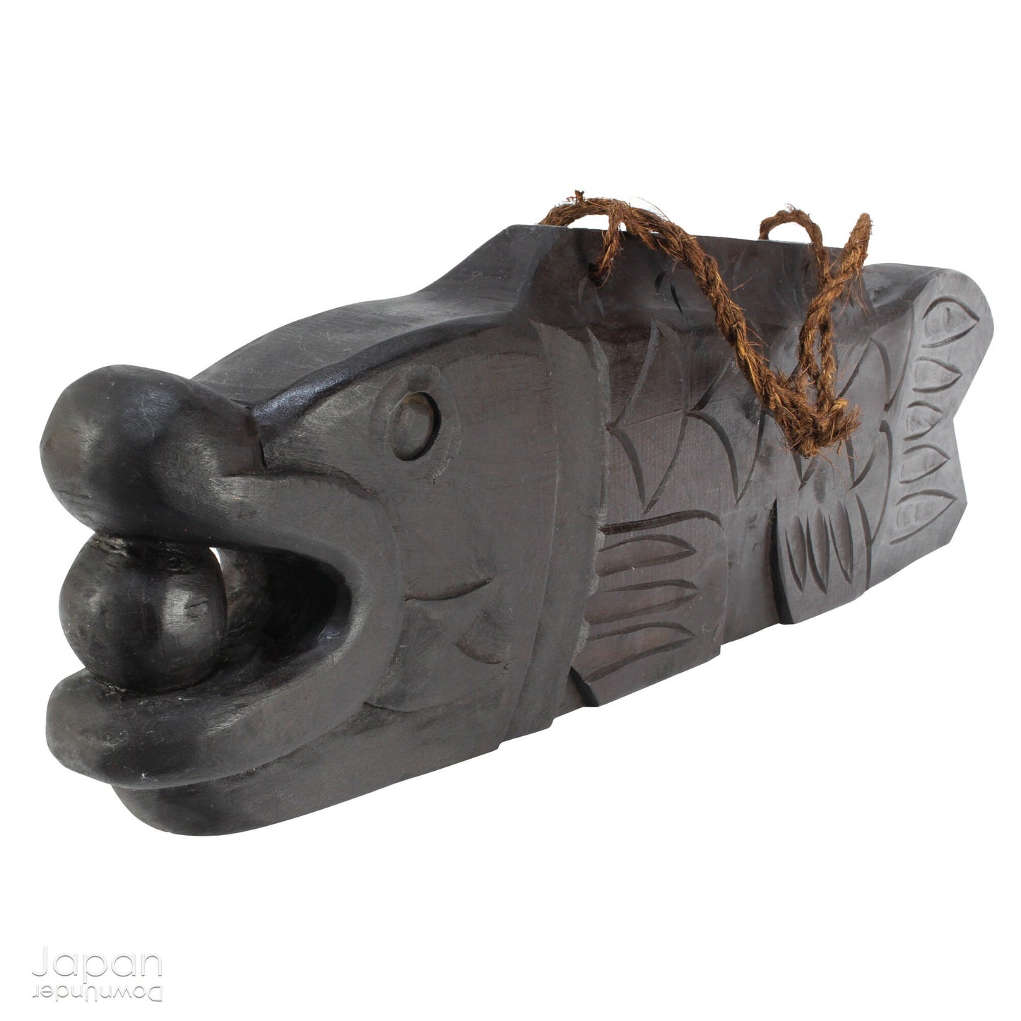 A vintage Buddhist temple gyoban; a  plank of wood shaped like a fish.  It is carved from   wood. The scales, big eye and fin, etched  into the wood,  give the fish form. There is a  round pearl in the fish mouth,  symbolizing unity.