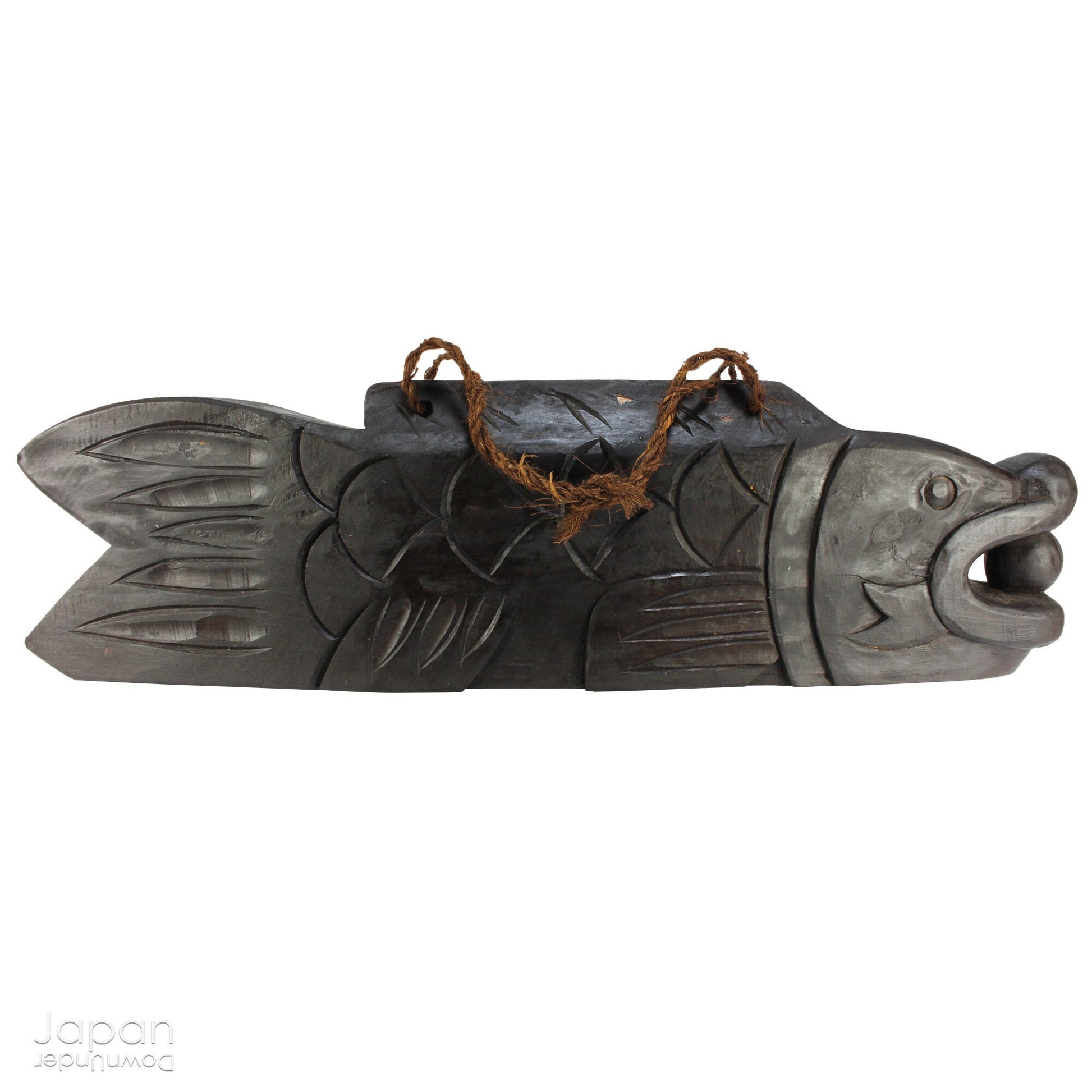 A vintage Buddhist temple gyoban; a  plank of wood shaped like a fish.  It is carved from   wood. The scales, big eye and fin, etched  into the wood,  give the fish form. There is a  round pearl in the fish mouth,  symbolizing unity.