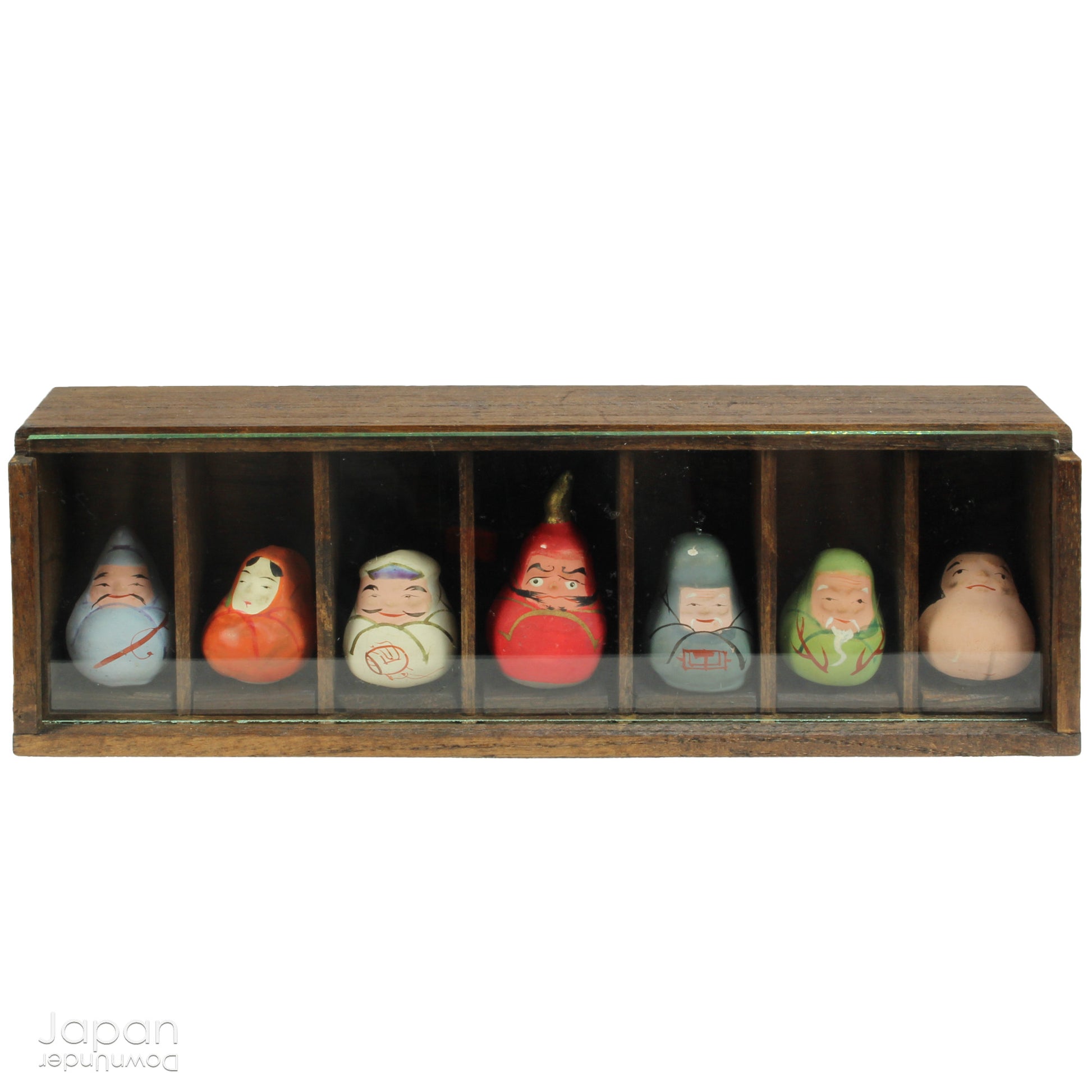 Invite good fortune and timeless tradition into your home with this quaint set of miniature antique Daruma charms. Housed in a charming wooden and glass display box, this unique collection adds an elegant and meaningful touch to your decor, perfect for any space seeking a blend of tradition, luck, and positive energy.

Crafted in the 1920s, this set features hand-painted clay Daruma figures representing the Seven Lucky Gods of Japan, each with its own powerful symbolism.