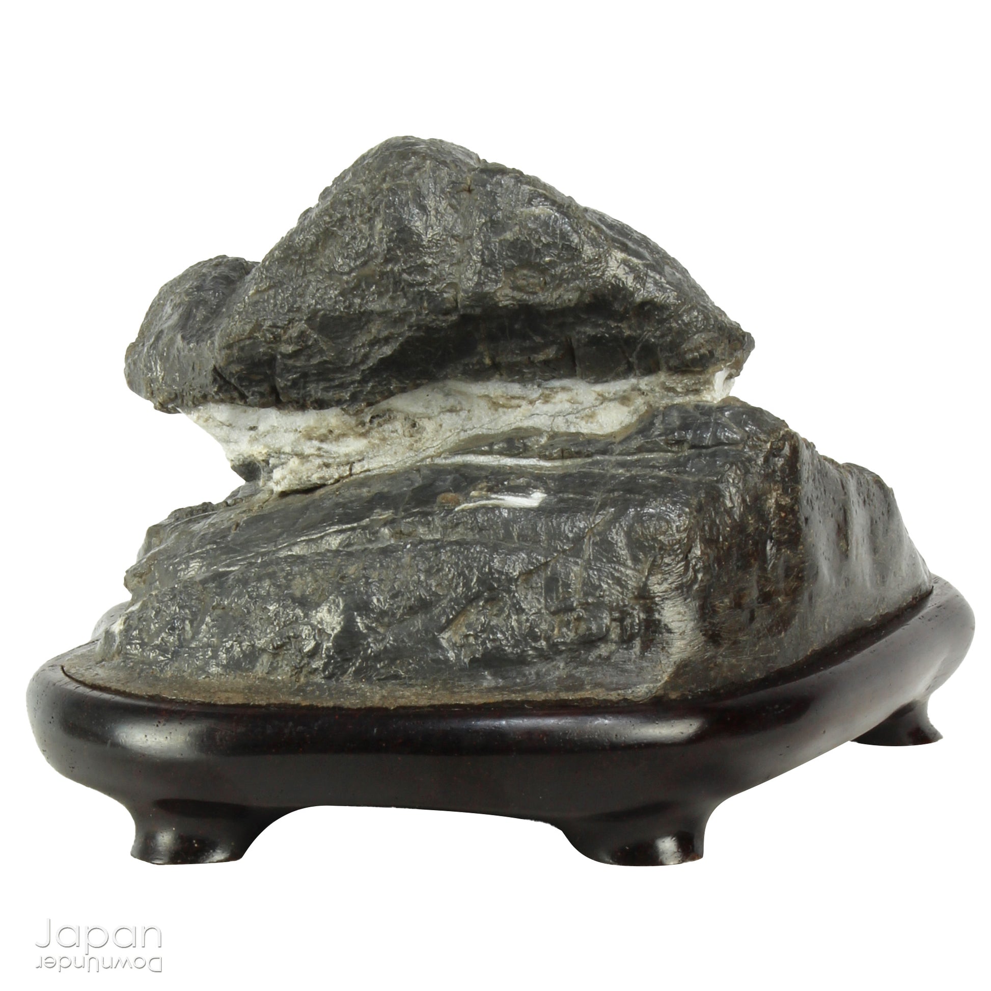 Immerse yourself in the meditative beauty of this captivating miniature suiseki - a traditional Japanese art form where nature is the true sculptor. Gracefully resting on a finely hand-carved ebony daiza (base), this stone embodies stillness and quiet strength, making it an ideal centerpiece for contemplative spaces, creative corners, or serene interiors.