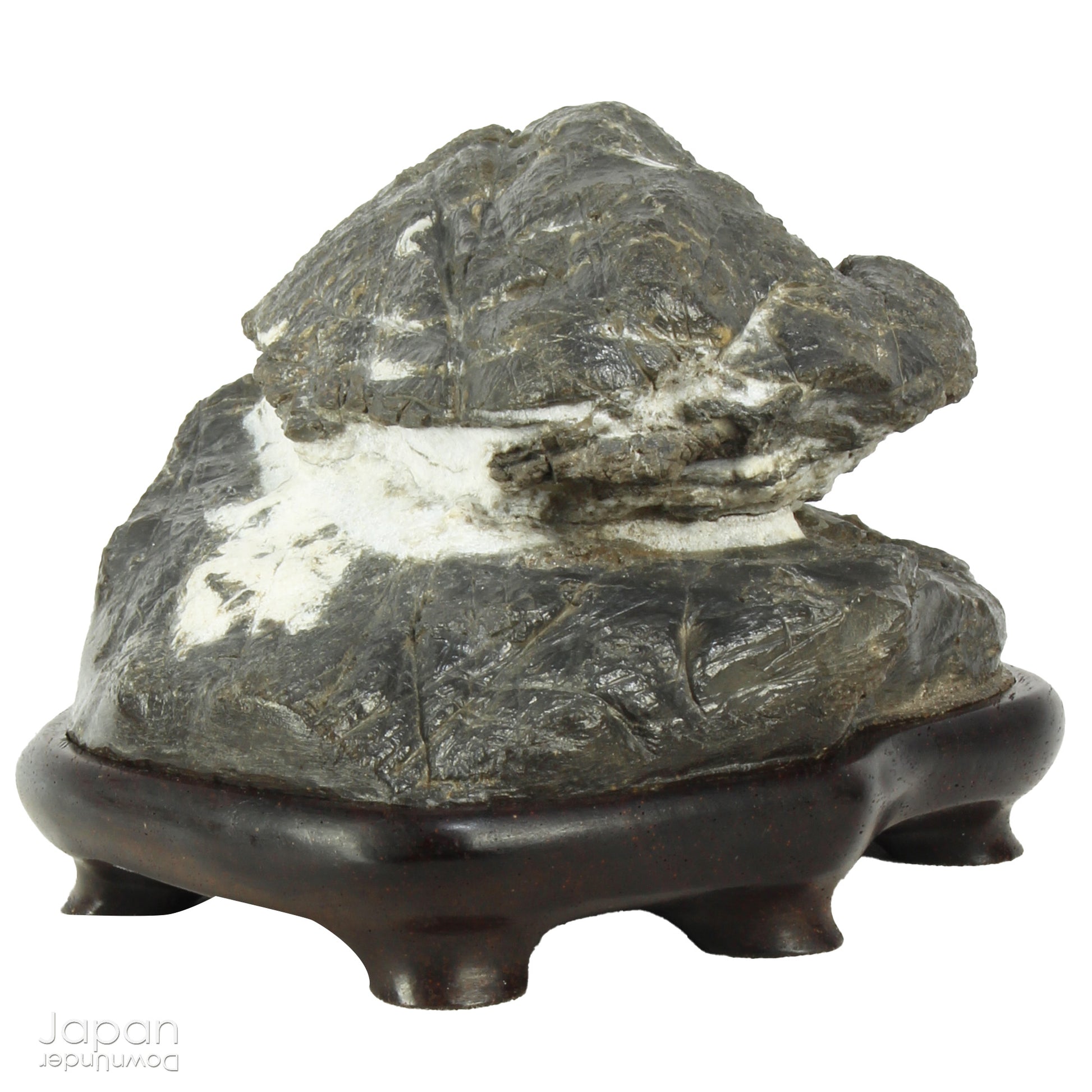 Immerse yourself in the meditative beauty of this captivating miniature suiseki - a traditional Japanese art form where nature is the true sculptor. Gracefully resting on a finely hand-carved ebony daiza (base), this stone embodies stillness and quiet strength, making it an ideal centerpiece for contemplative spaces, creative corners, or serene interiors.