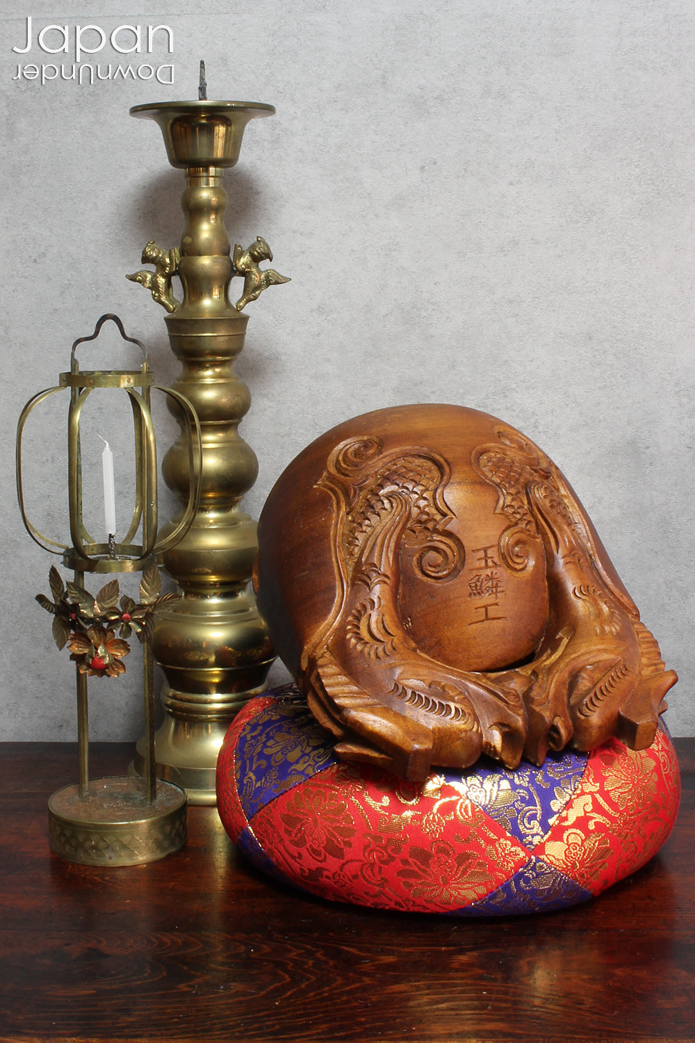 An antique Buddhist temple candle holder.    The gilded brass candle holder is a cylindrical shape, formed of spheres,  gradually decreasing in size as they move upwards. Just below the candle cup hang a pair of Japanese komainu, or lion dogs.